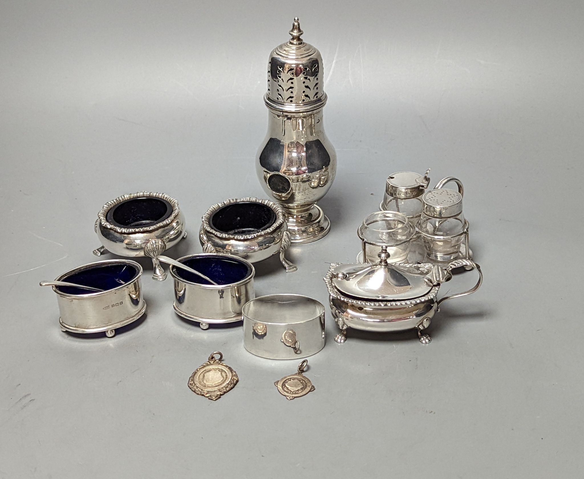 A late Victorian small silver condiment stand with three glass condiments, London, 1883, 49mm, other minor condiments and a silver sugar caster.